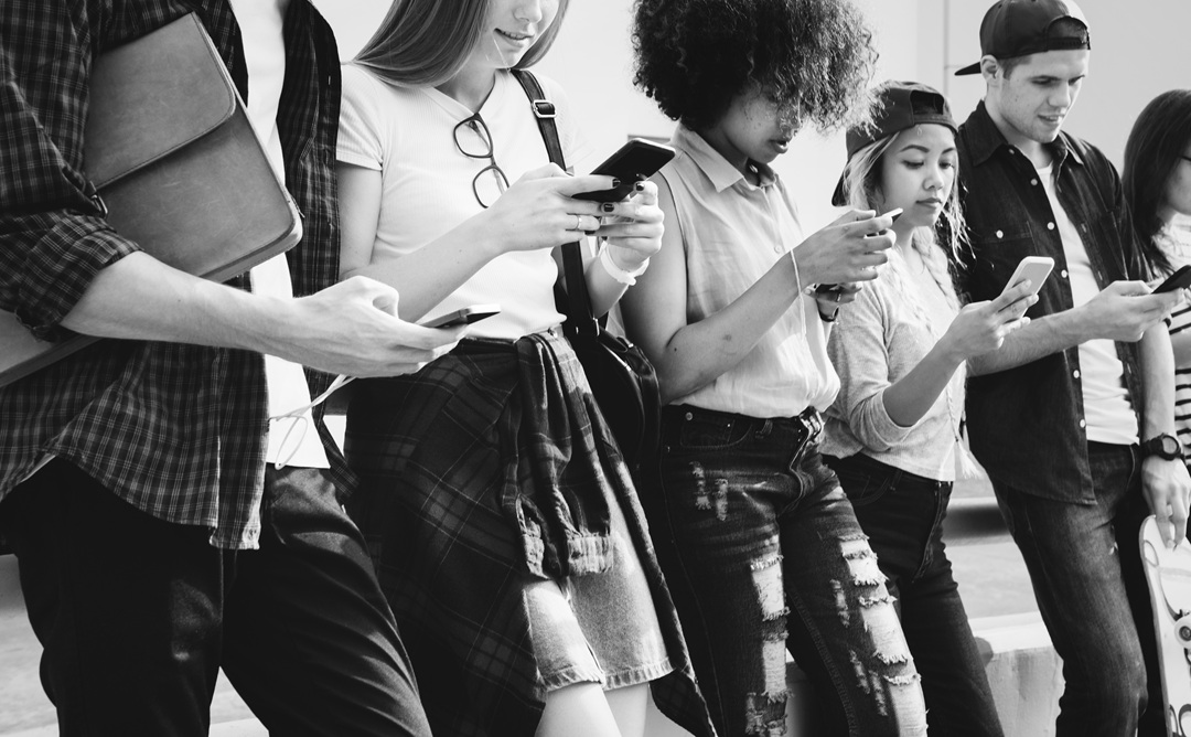 millennials using smartphones outdoors together